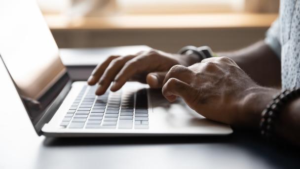 Image showing an identifiable person's hands typing on a laptop screen.