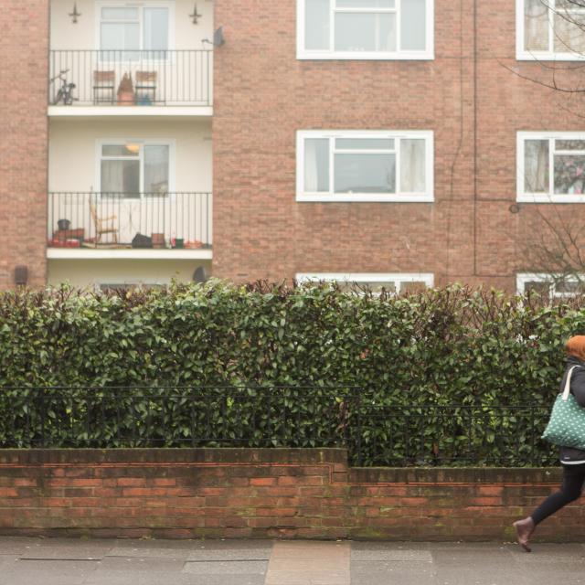 Image of a woman walking past a block of flats 