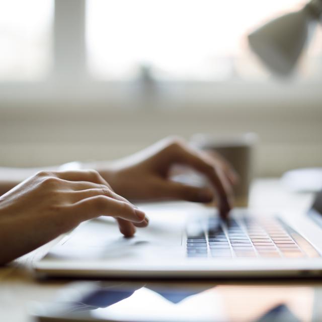 Close-up of hands typing on a laptop keyboard