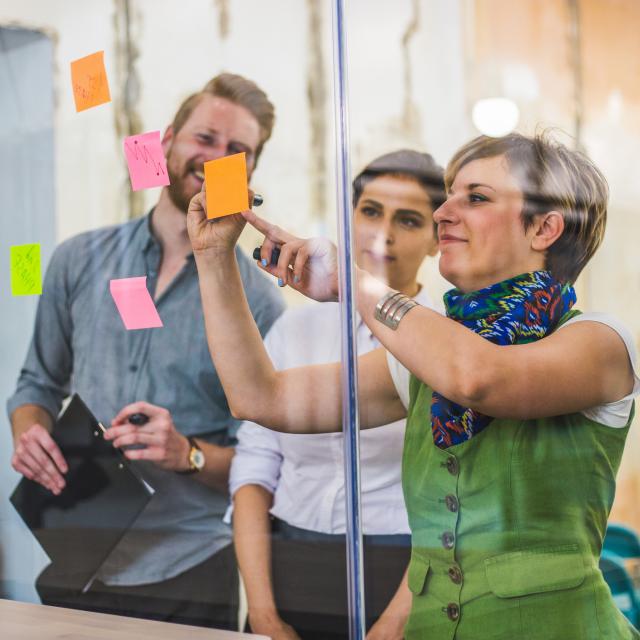 Three individuals discussing ideas with post-it notes