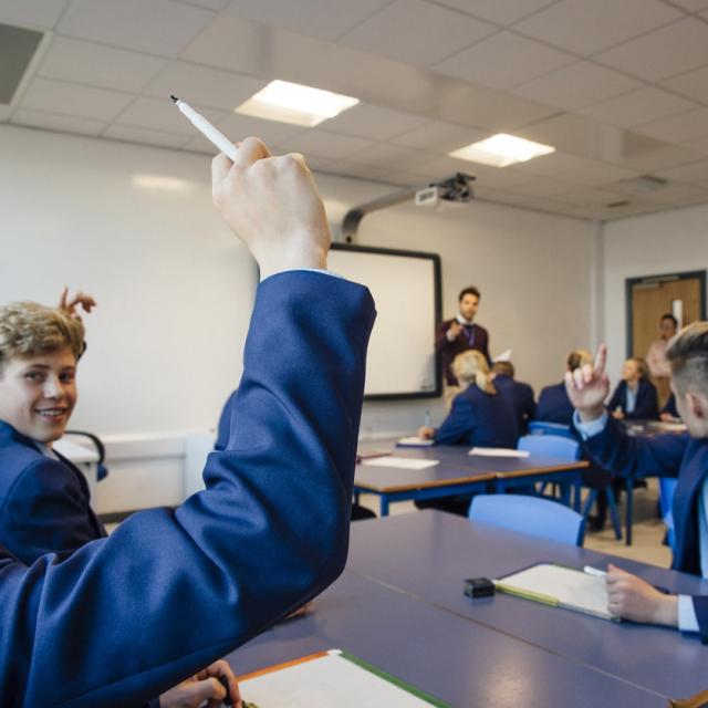 Children raising their hands in class.