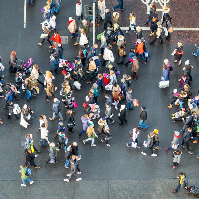 An image, taken from above, of people crossing the road at a busy junction.