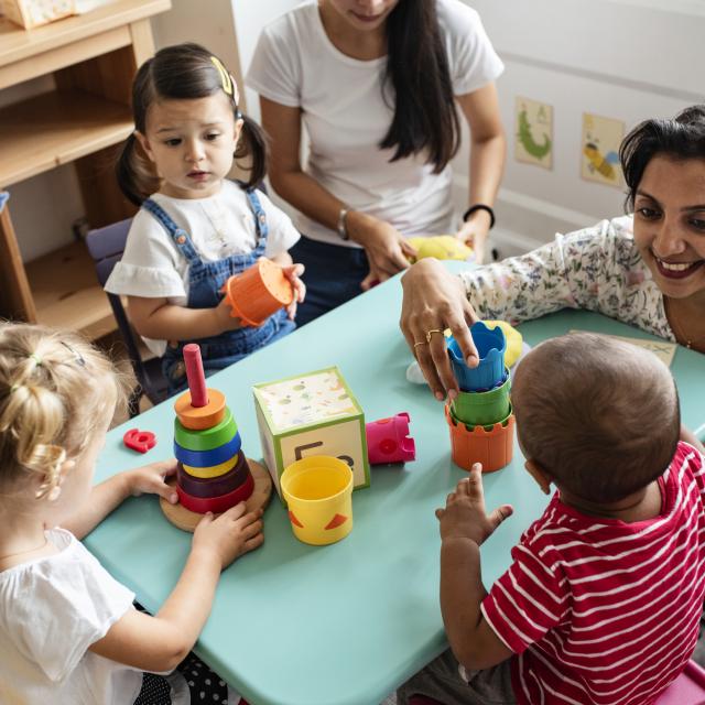 Nursery children playing with teacher in the classroom stock photo