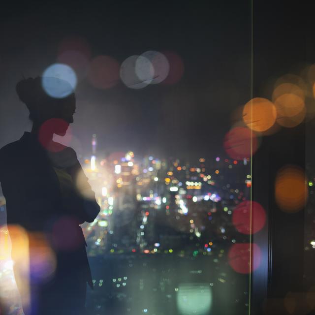 Silhouette of young adult woman standing in contemplation at night