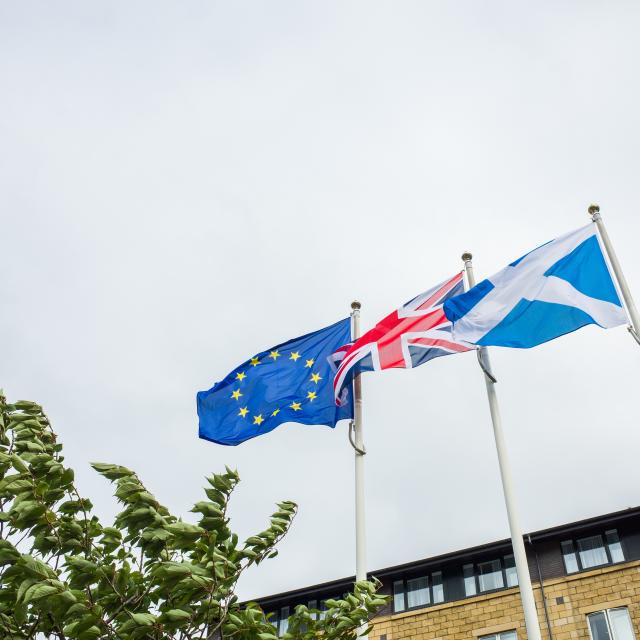 Scottish national flag, Union Jack and European Union flag flying together in the wind on a cloudy day in Edinburgh, Scotland.