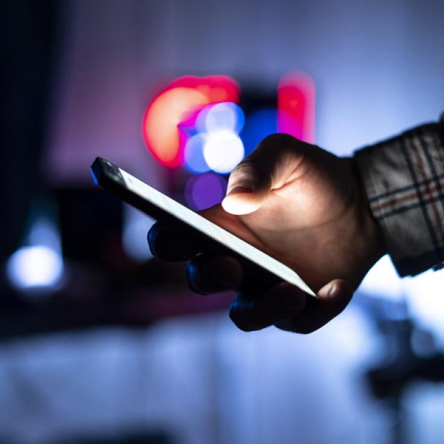 Person holding smartphone and scrolling on web page at night