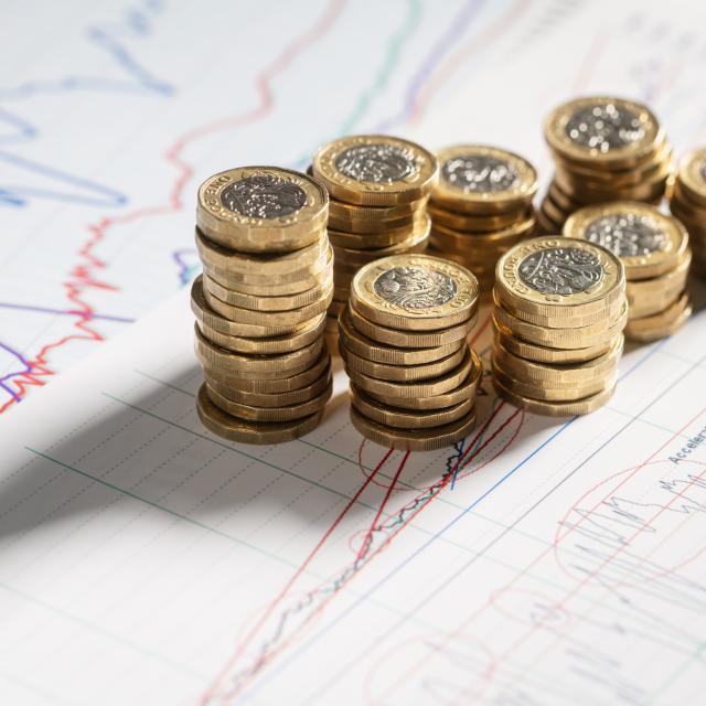 Stack of pound coins and charts