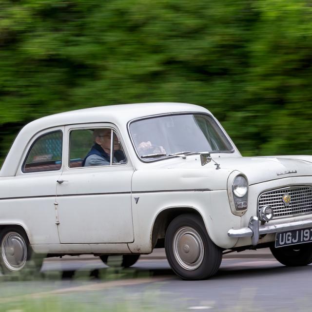 Ford Anglia classic car driving on a British road.