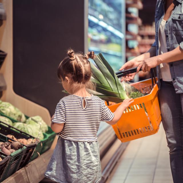 Mom and daughter shopping in vegetable aisle at the supermarket