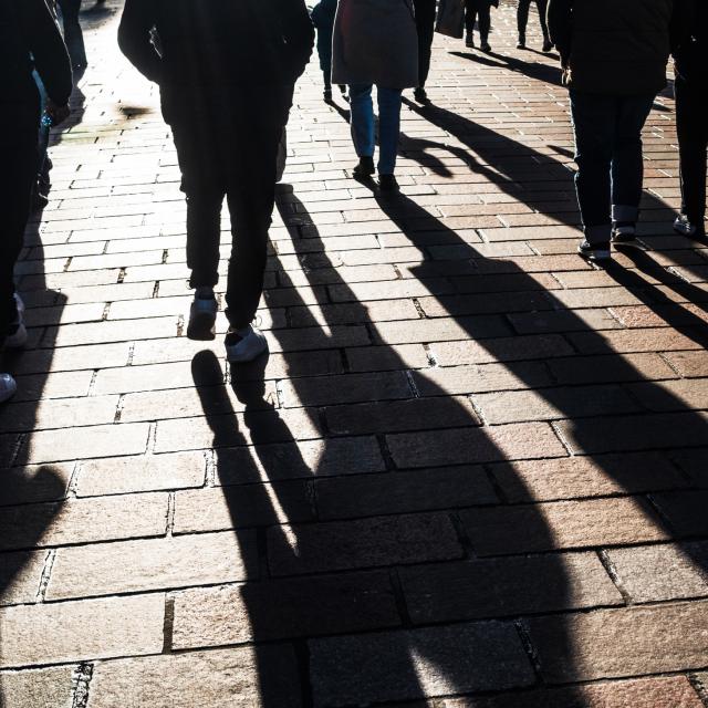 View of people and long shadows, walking on a British high street.