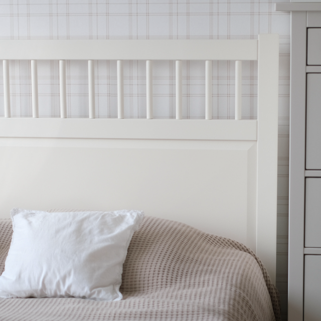 Direct angle image of a bed and chest of draws next to it. 