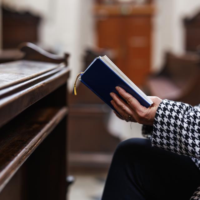 Someone reading or singing from a book in a church or religious building.
