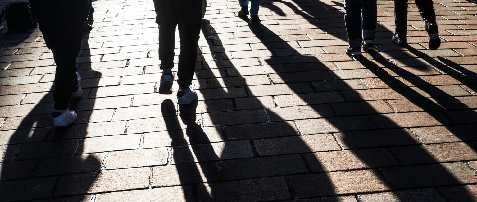 View of people and long shadows, walking on a British high street.