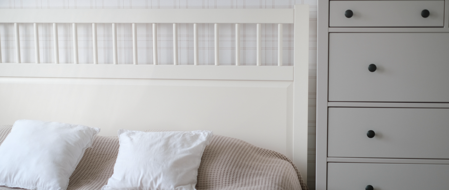 Direct angle image of a bed and chest of draws next to it. 