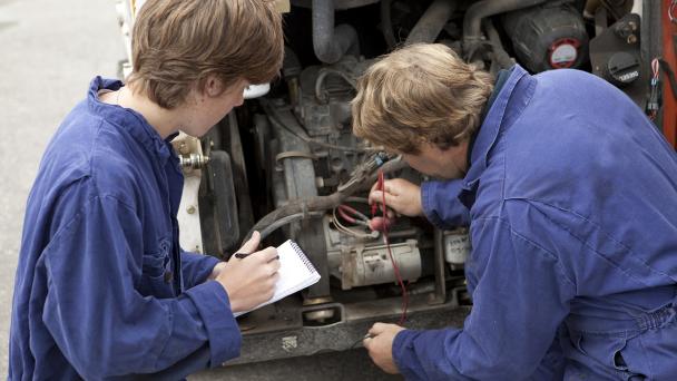 Two mechanics in front of a vehicle