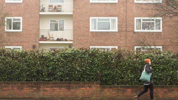 Image of a woman walking past a block of flats