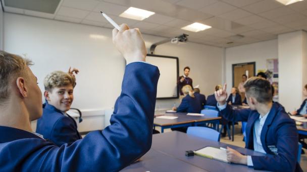 Children raising their hands in class.