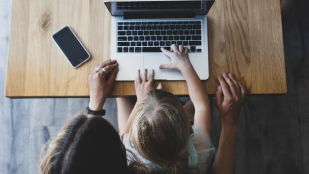 A mother and child sitting at a laptop filling out an online survey