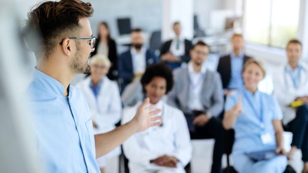 Male healthcare worker giving presentation to group of people in board room