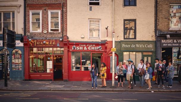 Diverse group of people waiting at bus stop on summer day in UK