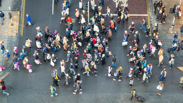 An image, taken from above, of people crossing the road at a busy junction.