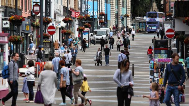 People walking in different directions on UK high street.