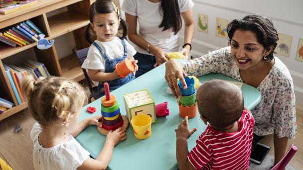 Nursery children playing with teacher in the classroom stock photo