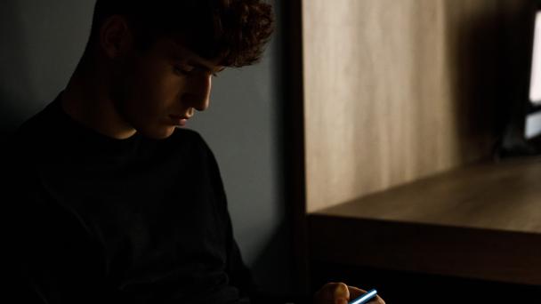 Young man using his phone in a dark room