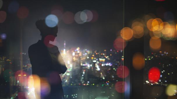 Silhouette of young adult woman standing in contemplation at night