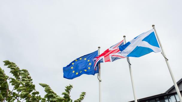 Scottish national flag, Union Jack and European Union flag flying together in the wind on a cloudy day in Edinburgh, Scotland.