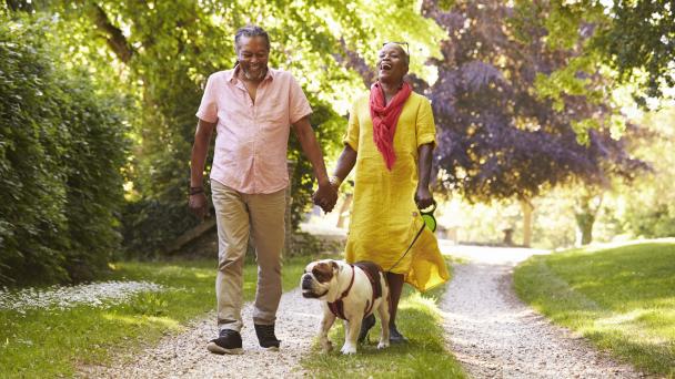 Couple walking their dog in rural/green landscape.