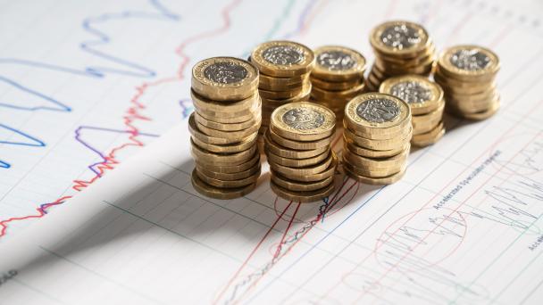 Stack of pound coins and charts