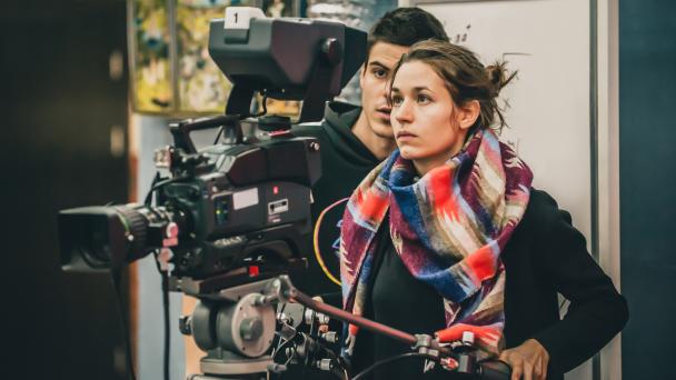 Cameraman and assistant shooting the film scene with camera in film studio