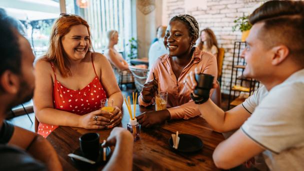 Group of young adults sitting around a table smiling