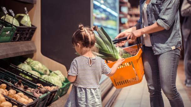 Mom and daughter shopping in vegetable aisle at the supermarket