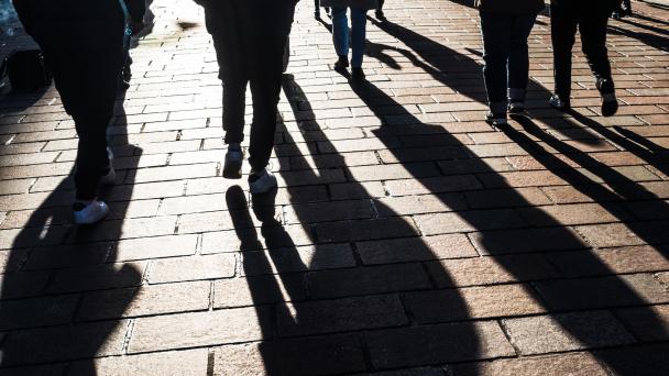 View of people and long shadows, walking on a British high street.