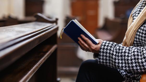 Someone reading or singing from a book in a church or religious building.