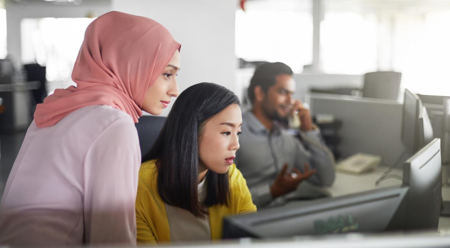 Employees look at a shared screen in an office