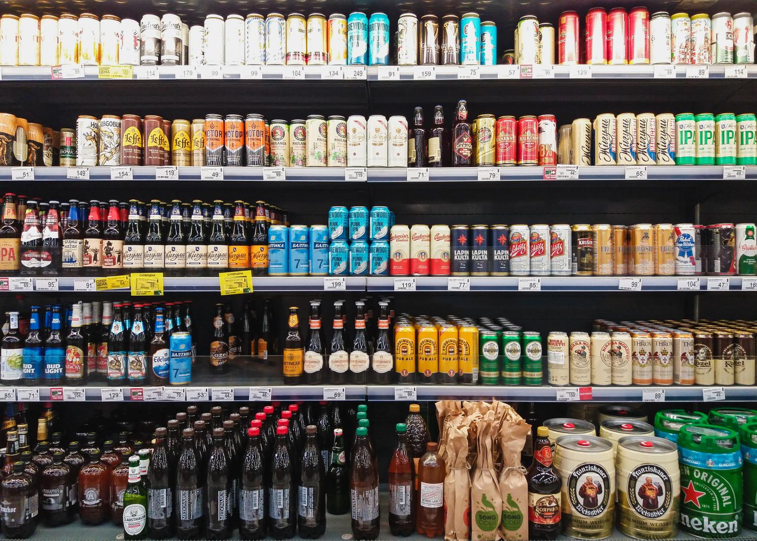 Beer bottles and cans lined on grocery shelves