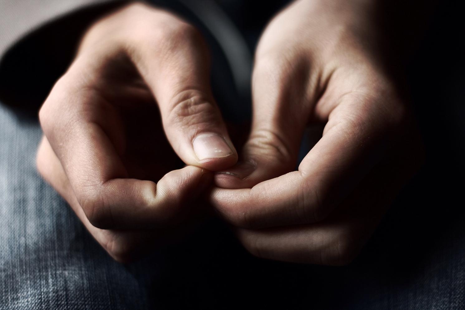 A pair of hands anxiously laying in lap